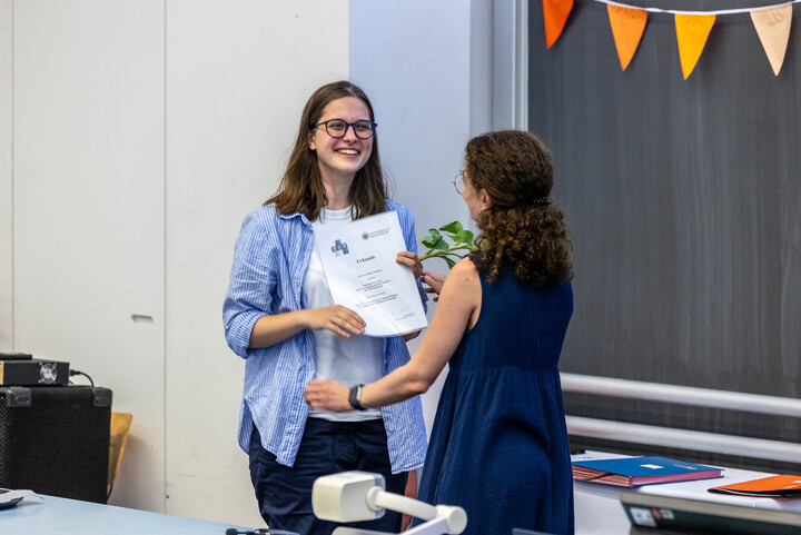 Studentin bekommt Urkunde überreicht.