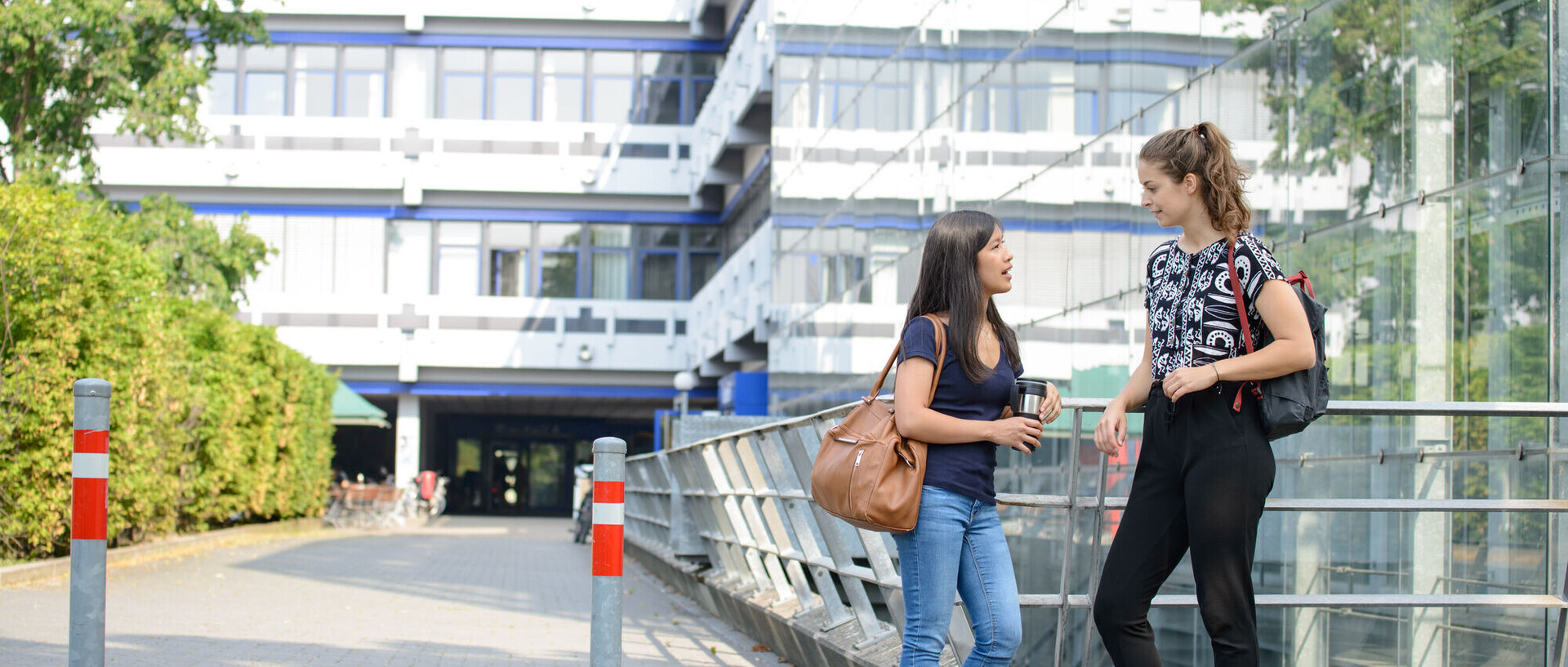 Zwei Studierende stehen vor dem A5 Gebäude und unterhalten sich. 