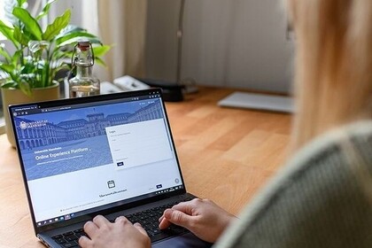 Eine junge Frau sitzt am Schreibtisch in ihrer Wohnung und arbeitet am Laptop. Auf dem Bildschirm ist die Website der Universität Mannheim zu erkennen. Link: Instagram-Post Bewerbungsphase endet
