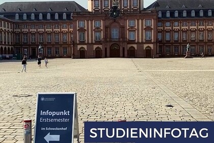 Sommertag auf dem Ehrenhof der Universität Mannheim. Vorne ein Aufsteller, der auf den Studieninfotag am 16. November 2022 hinweist.